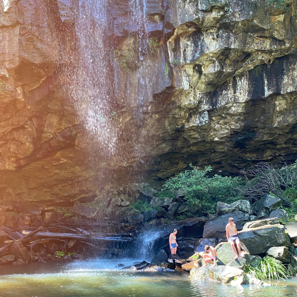 Teenagers play in the pool at the foot of a waterfall