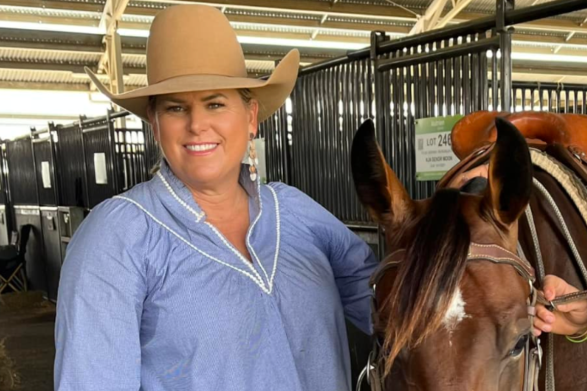 an image of a woman in a wide brimmed hat and a blue shirt standing next to a horse